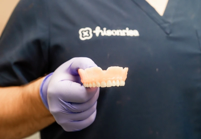 Close-up of a snap-on denture model held in a gloved hand.