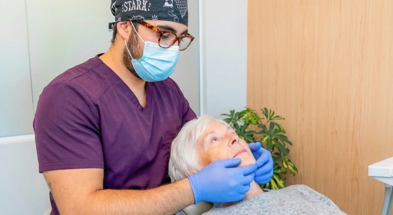 Clinician examining a patient during a full-arch implant consultation.