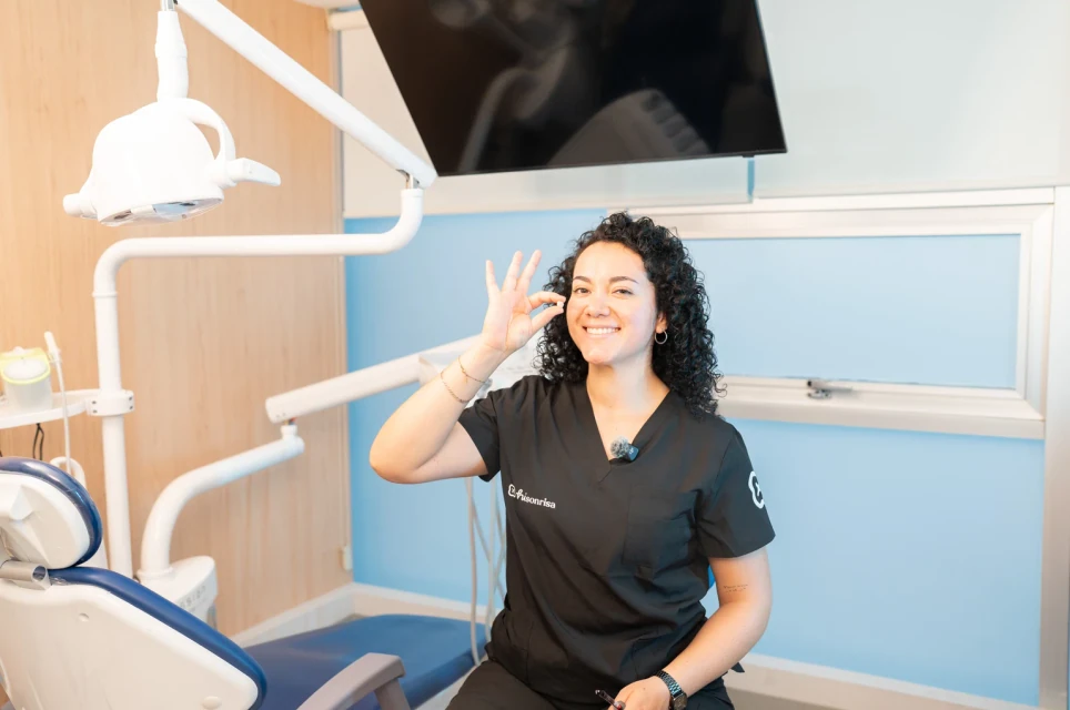 Dentista de hisonrisa sosteniendo una corona dental en un consultorio.