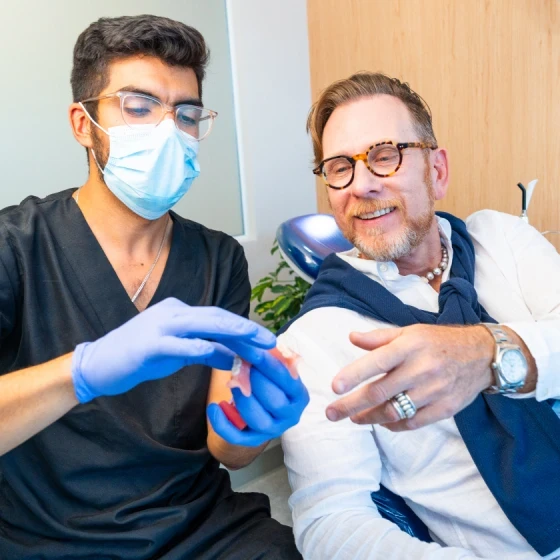 Dentista explicando un plan de tratamiento de arco completo a un paciente en hisonrisa.