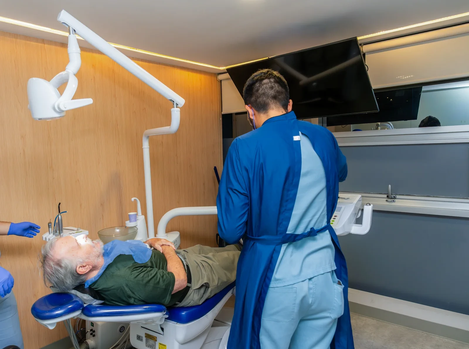 A patient rests in a hisonrisa treatment room while the dental team prepares an examination.