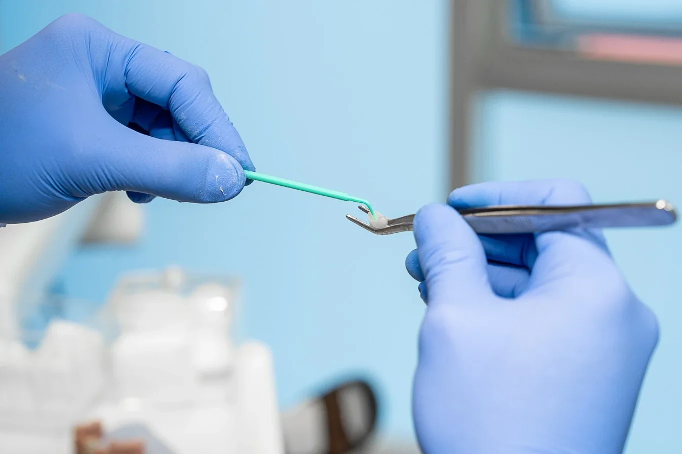 Gloved hands holding dental instruments during restorative preparation.