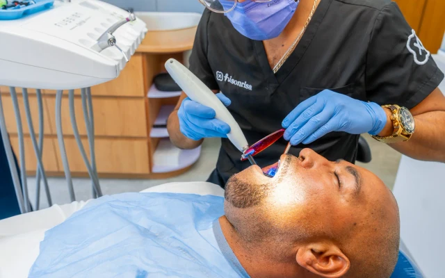 Dentist using a curing light during restorative care at hisonrisa in Mexico City.