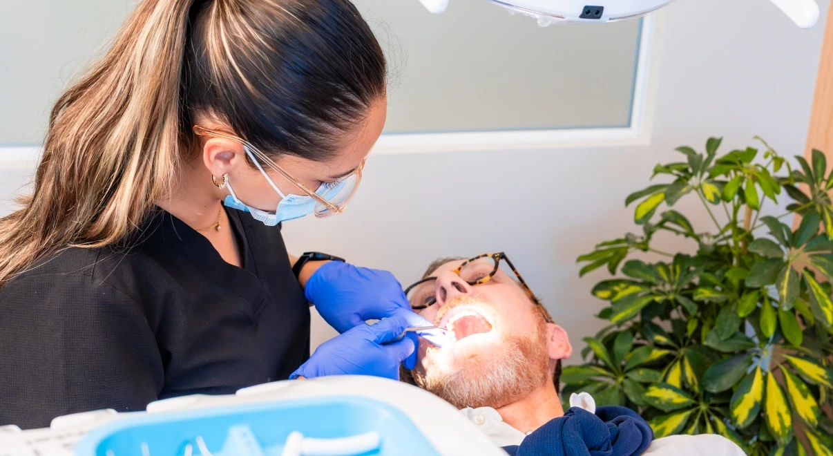 Clinician checking a patient during a deep cleaning evaluation at hisonrisa in Roma Sur.
