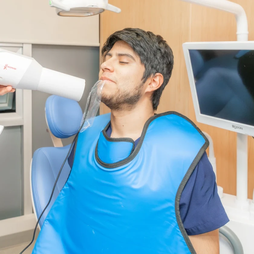 Patient during a dental X-ray or urgent exam visit at hisonrisa in Roma Sur, Mexico City.