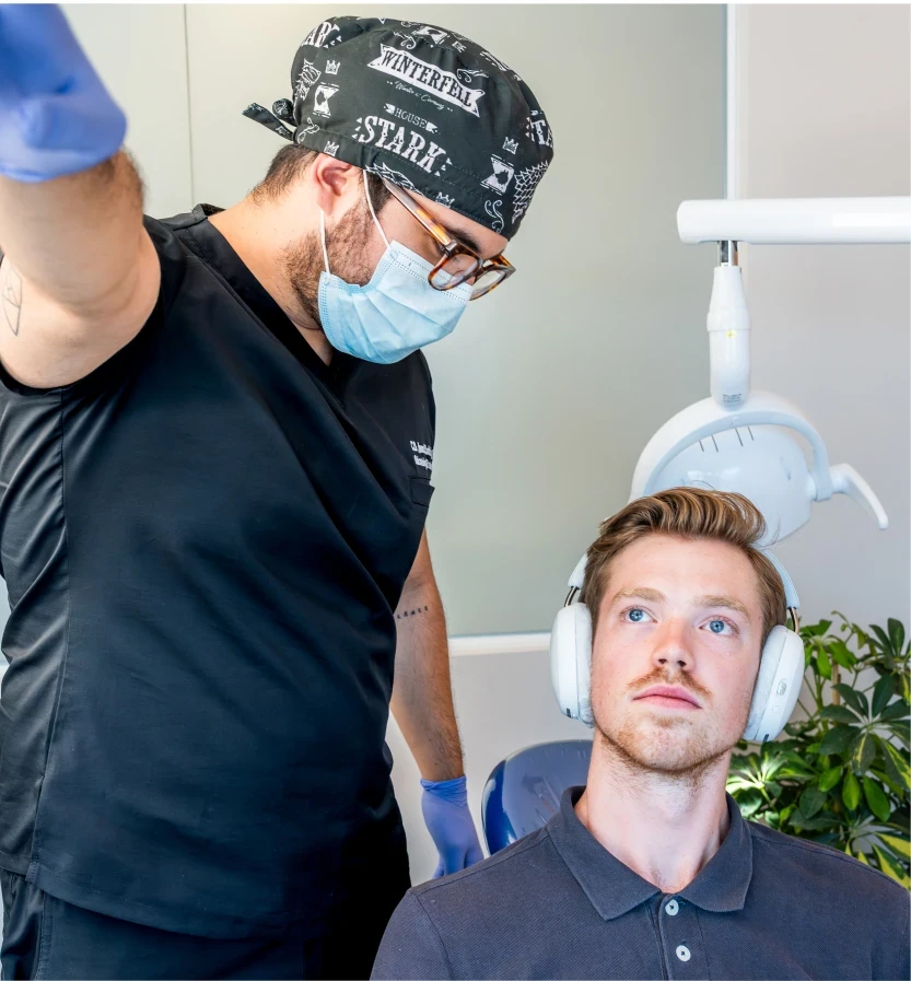 Dentist guiding a patient wearing headphones before treatment at hisonrisa in Roma Sur.