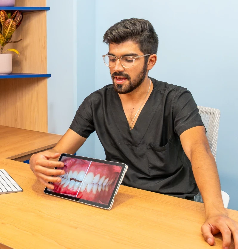 Dentist in Roma Sur showing a smile design on a tablet during a consultation in Mexico City.