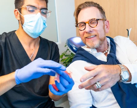 Dentist explaining treatment with a dental model to a patient at hisonrisa in Roma Sur.