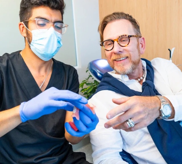 Dentist explaining treatment with a dental model to a patient at hisonrisa in Roma Sur.