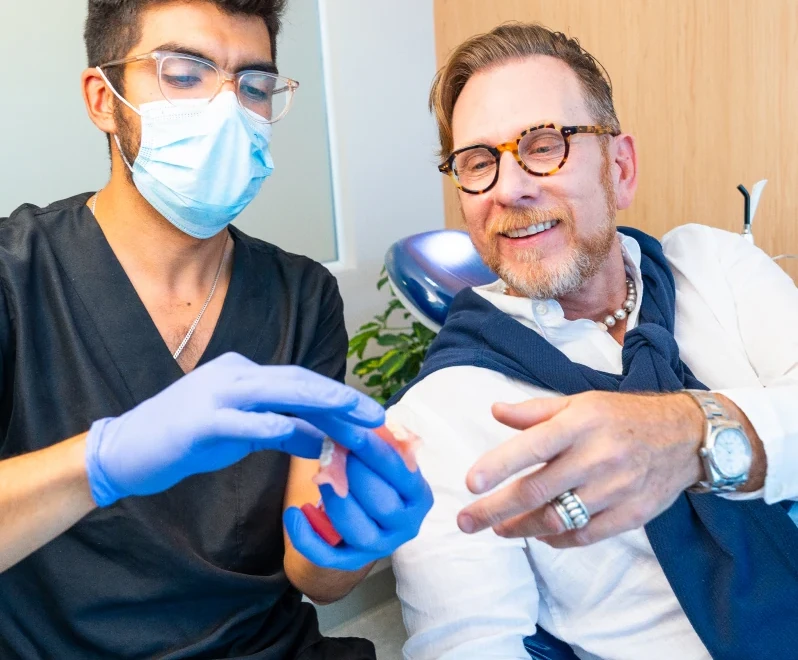 Dentist explaining an implant treatment model to a patient in Roma Sur, Mexico City.