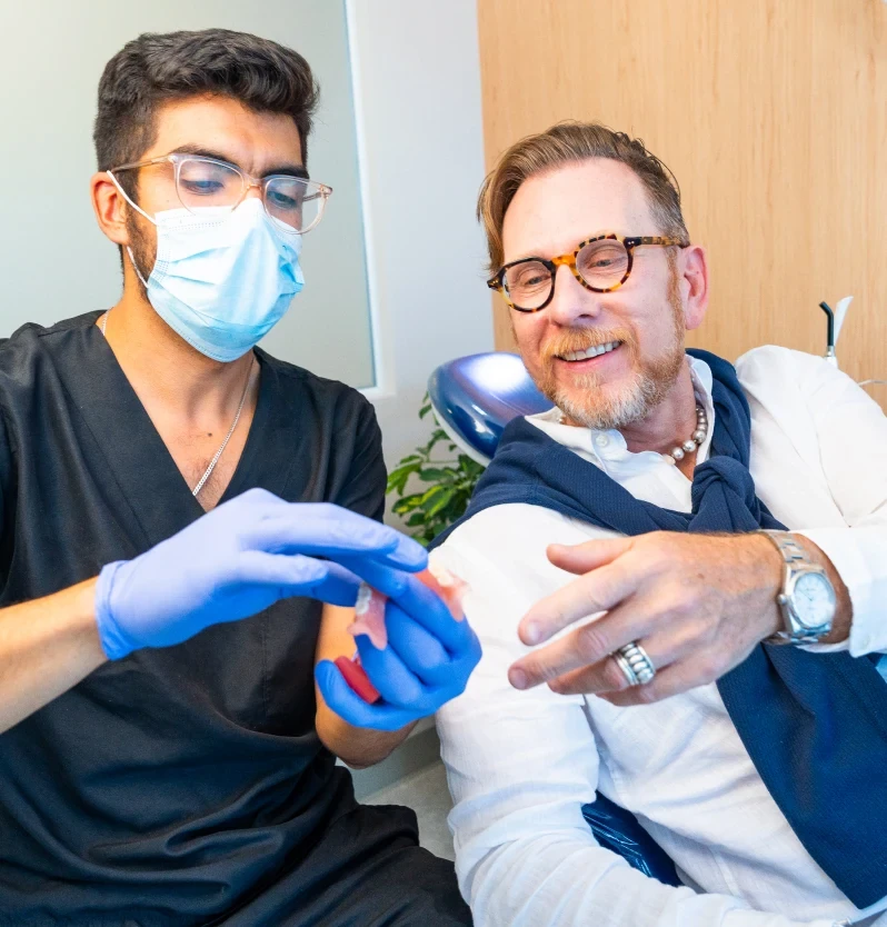 Dentist explaining a dental treatment model to a patient.