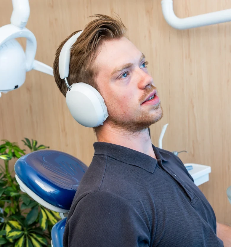 Patient relaxing with headphones in the treatment chair at hisonrisa in Roma Sur.