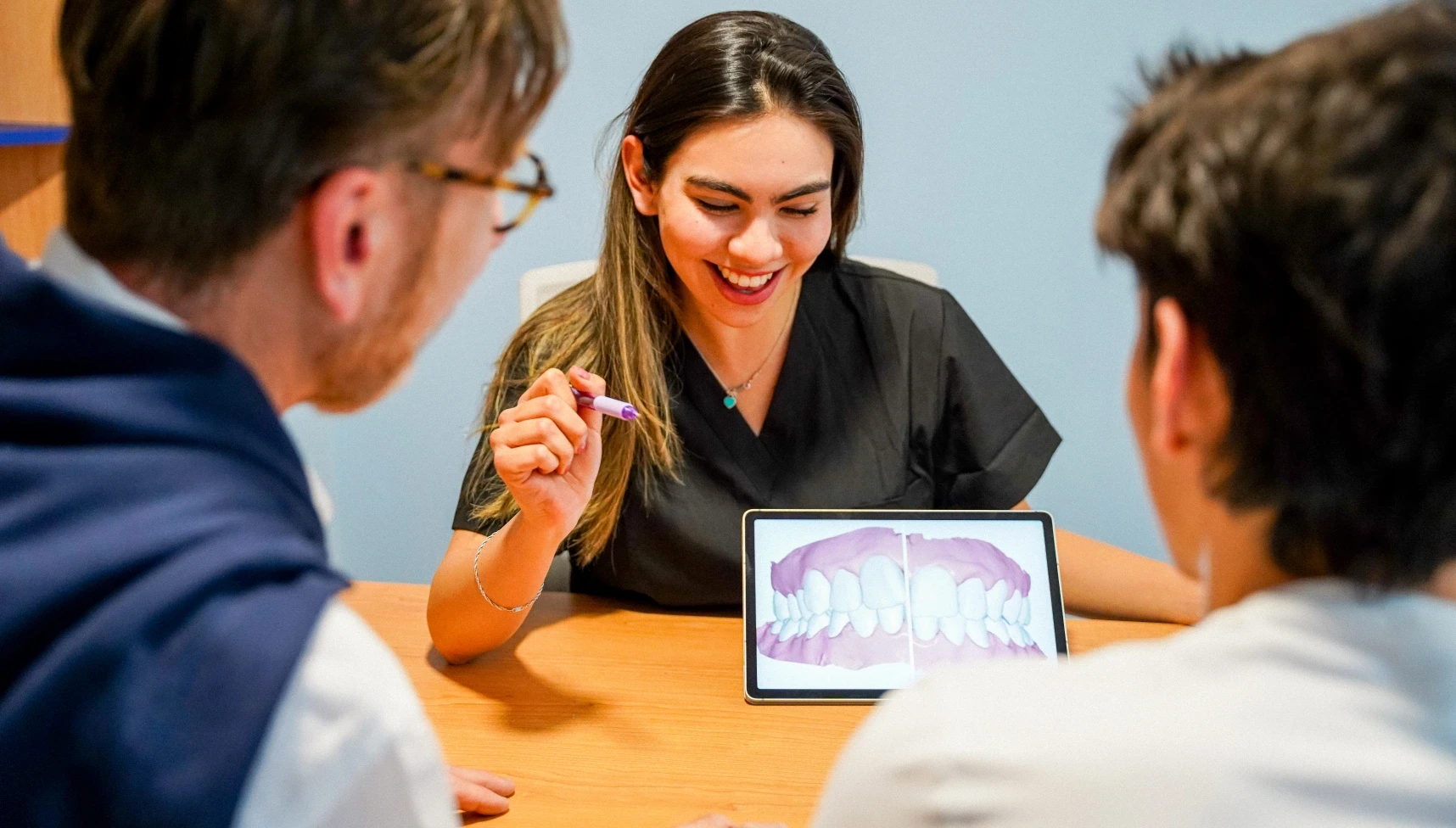 hisonrisa dentist explaining a smile plan to two patients using a tablet.