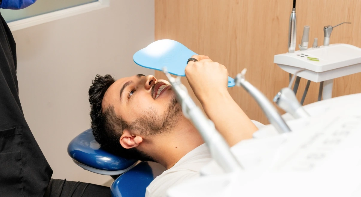Patient checking tooth shade during a professional whitening appointment.