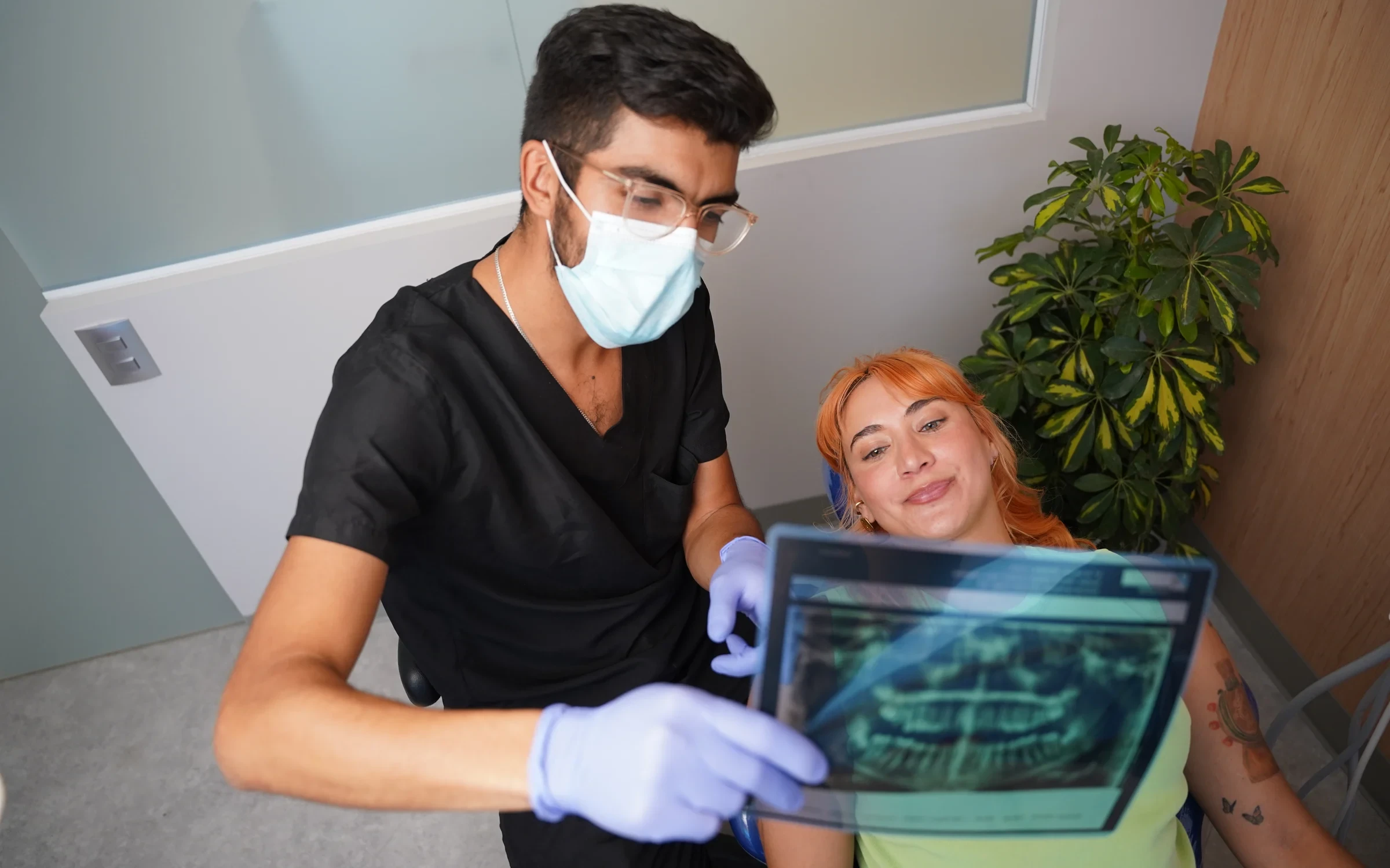 Dentista de hisonrisa revisando una radiografía de muelas del juicio con una paciente en Roma Sur, CDMX.